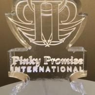 Clear acrylic trophy engraved “Pinky Promise International” on a dark background