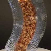 Close-up of an ice sculptured curving tube food display filled with shrimp against a dark background