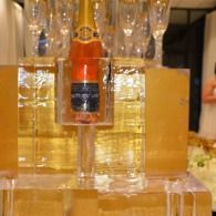 Champagne bottle chilling in an ice sculpture with stacked glasses and warm golden lighting