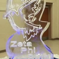 Illuminated Zeta Phi sign with a dove outline in a hallway, glowing purple and white