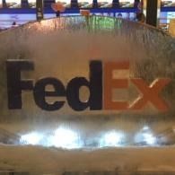 FedEx logo on a frosted glass-like ice sculptured panel with bright lights reflecting below