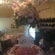 Elegant floral centerpiece in a crystal vase on a decorated table, with pink and purple flowers in a banquet hall