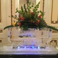 Clear crystal flower vase with red and green floral arrangement on a decorative table display