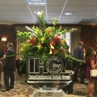 Large floral arrangement with IHG logo at an indoor event hall entrance