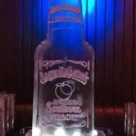 Clear bottle with a label, lit by blue and red lights against a dark backdrop.