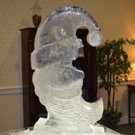 Transparent ice sculpture of a crescent shaped Santa head in an indoor setting