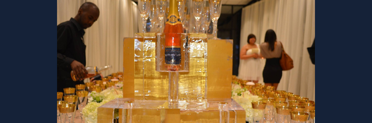 A champagne tower on a table, with guests in the background at an indoor celebration.