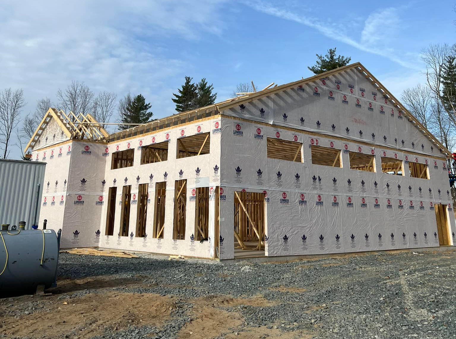 Construction of a wood-framed building; exterior walls covered in white sheathing; blue sky.