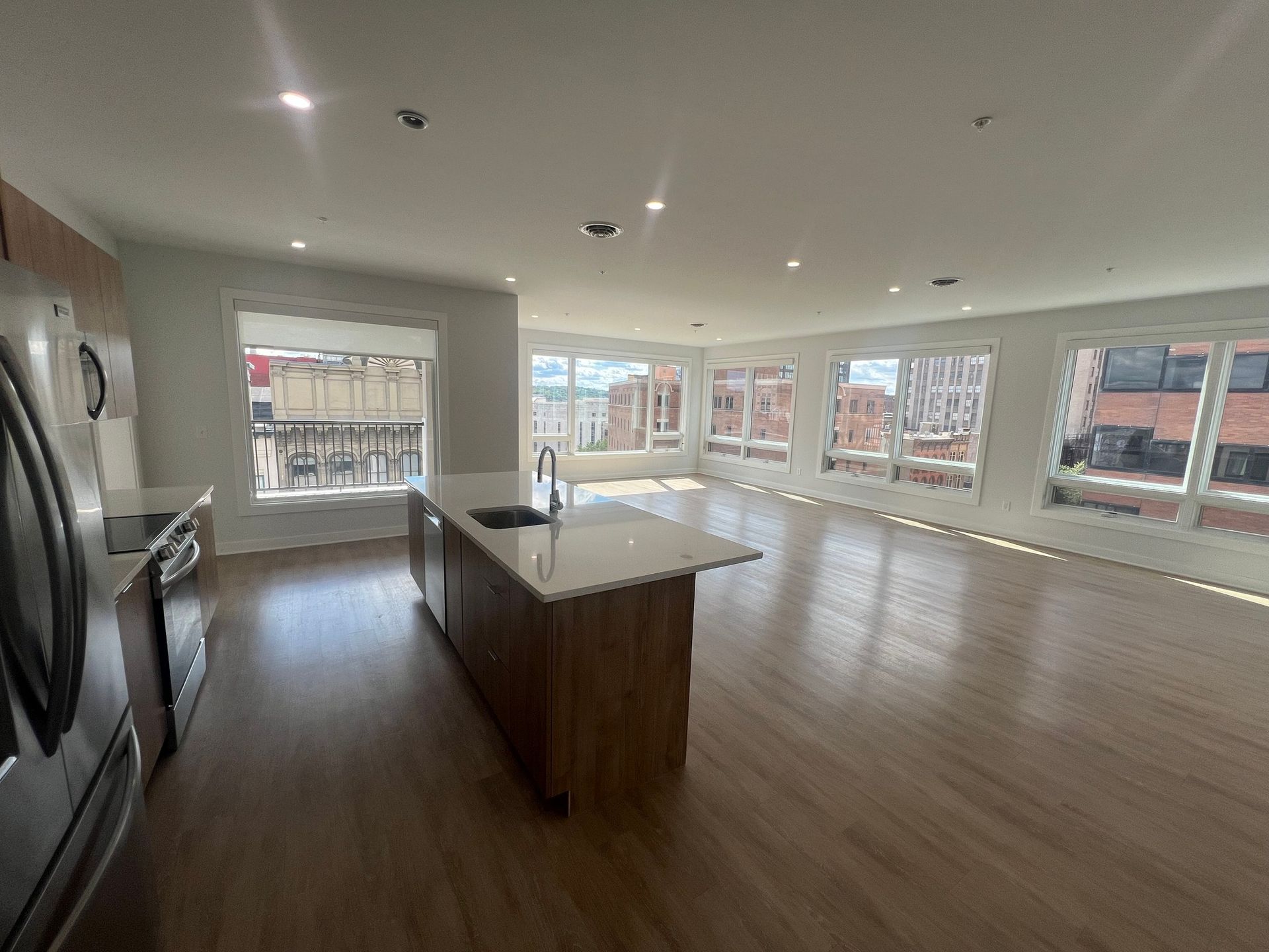 Spacious modern kitchen with island and large windows, hardwood floors, and stainless steel appliances.
