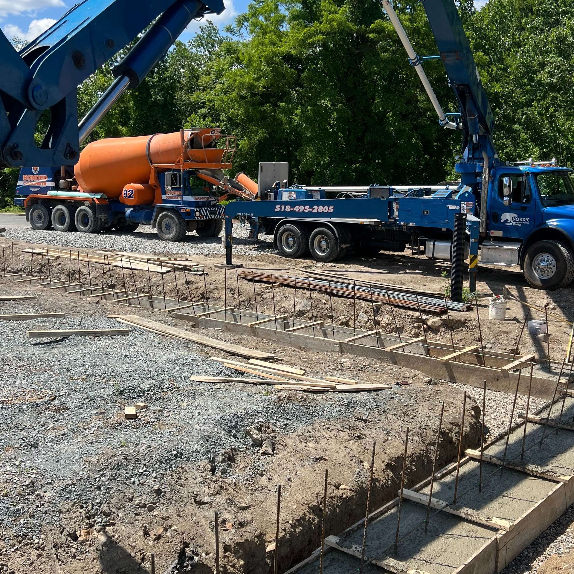 Concrete being poured at a construction site by a pump truck from a mixer truck.
