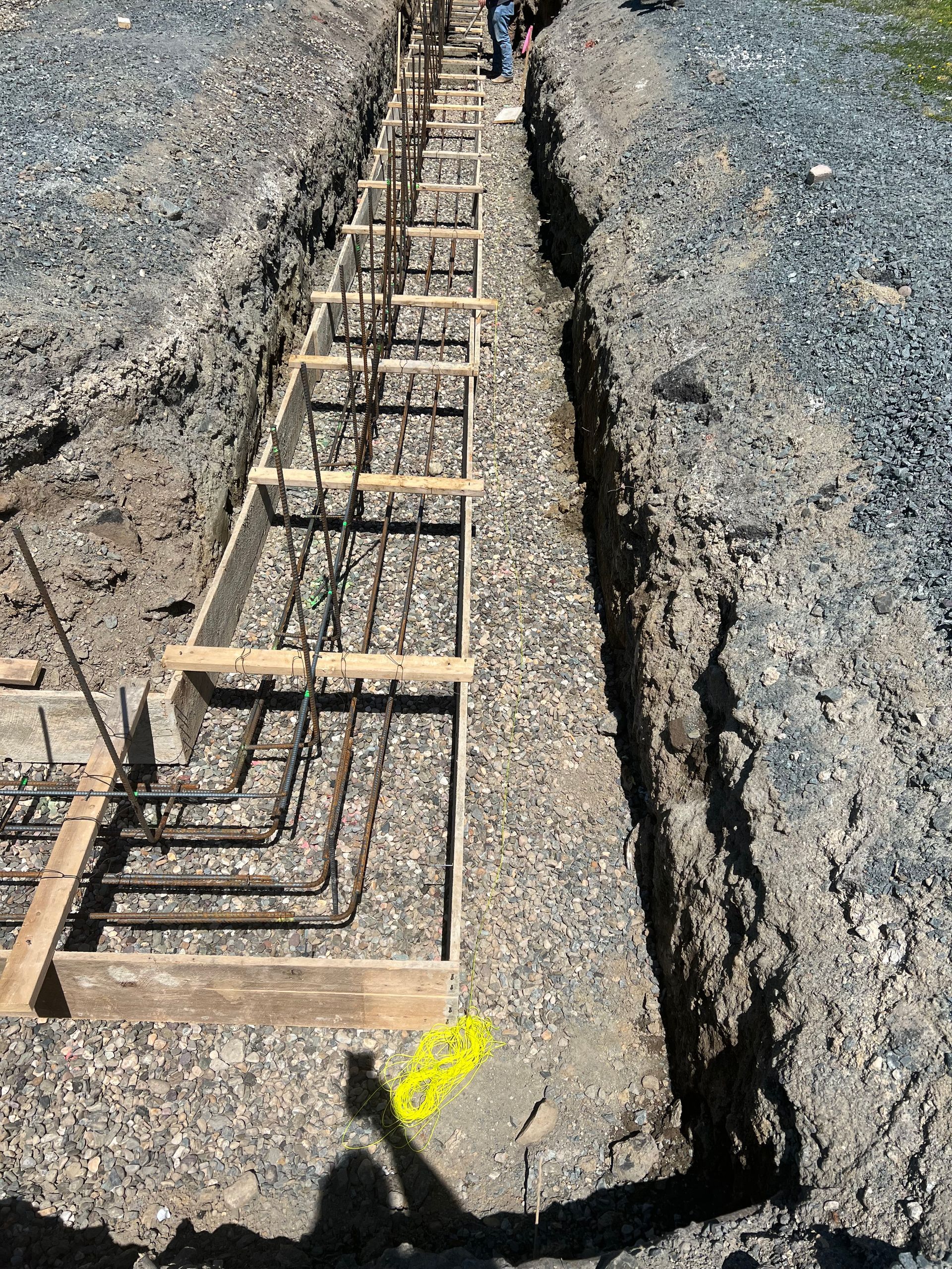 Construction site: wooden forms and rebar in a trench, prepared for concrete foundation.