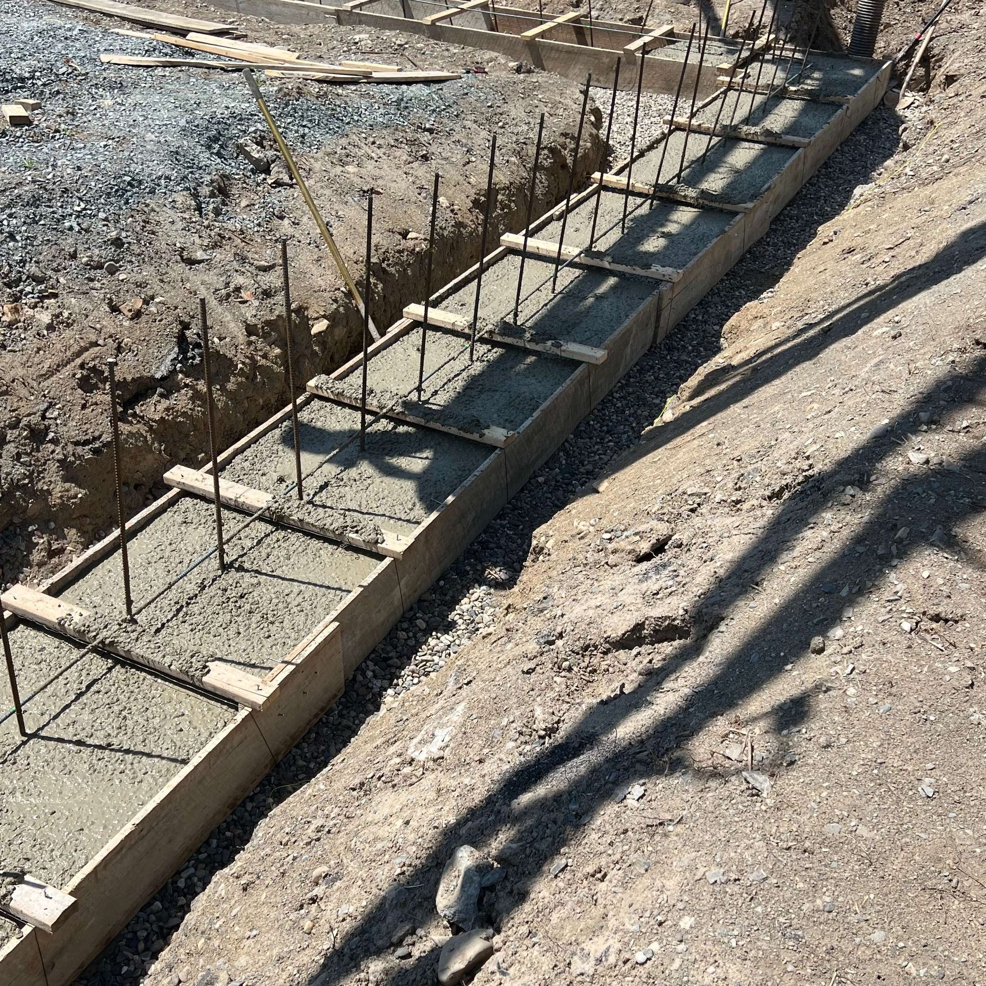 Wooden forms with rebar hold concrete for a construction project on a hillside.