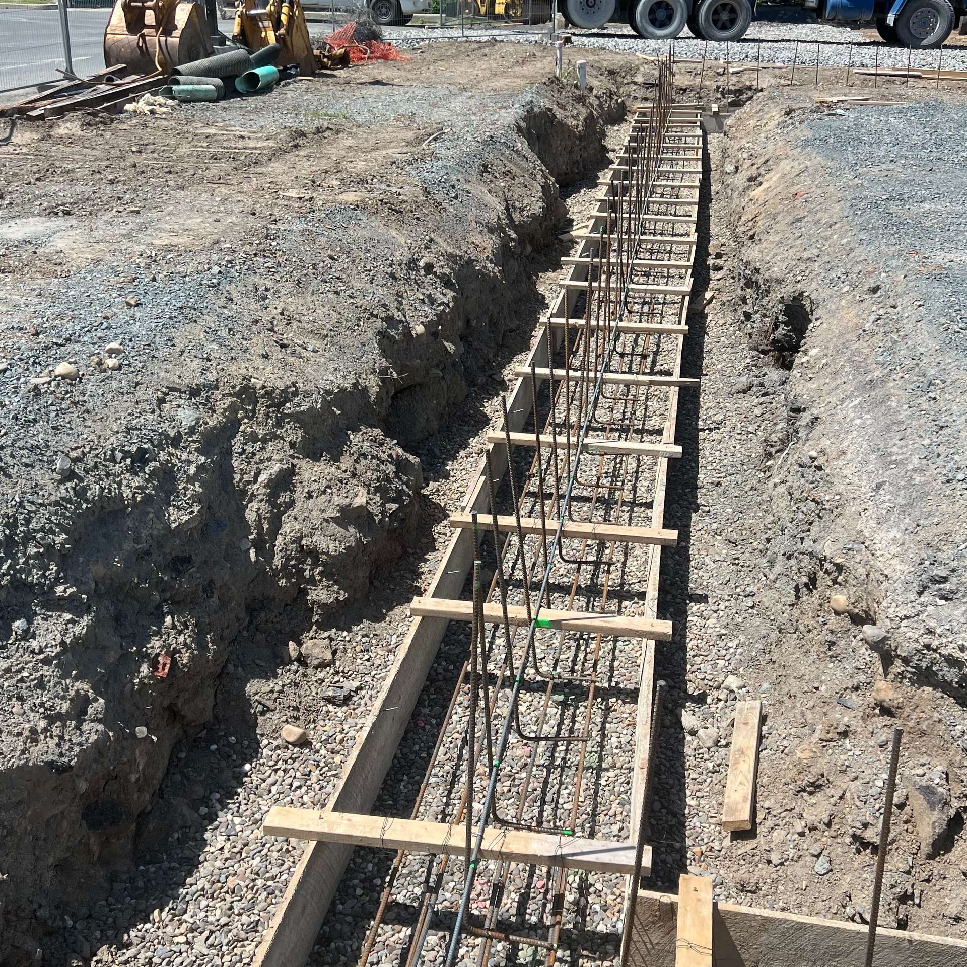 Construction site: concrete foundation formwork with rebar in a trench.