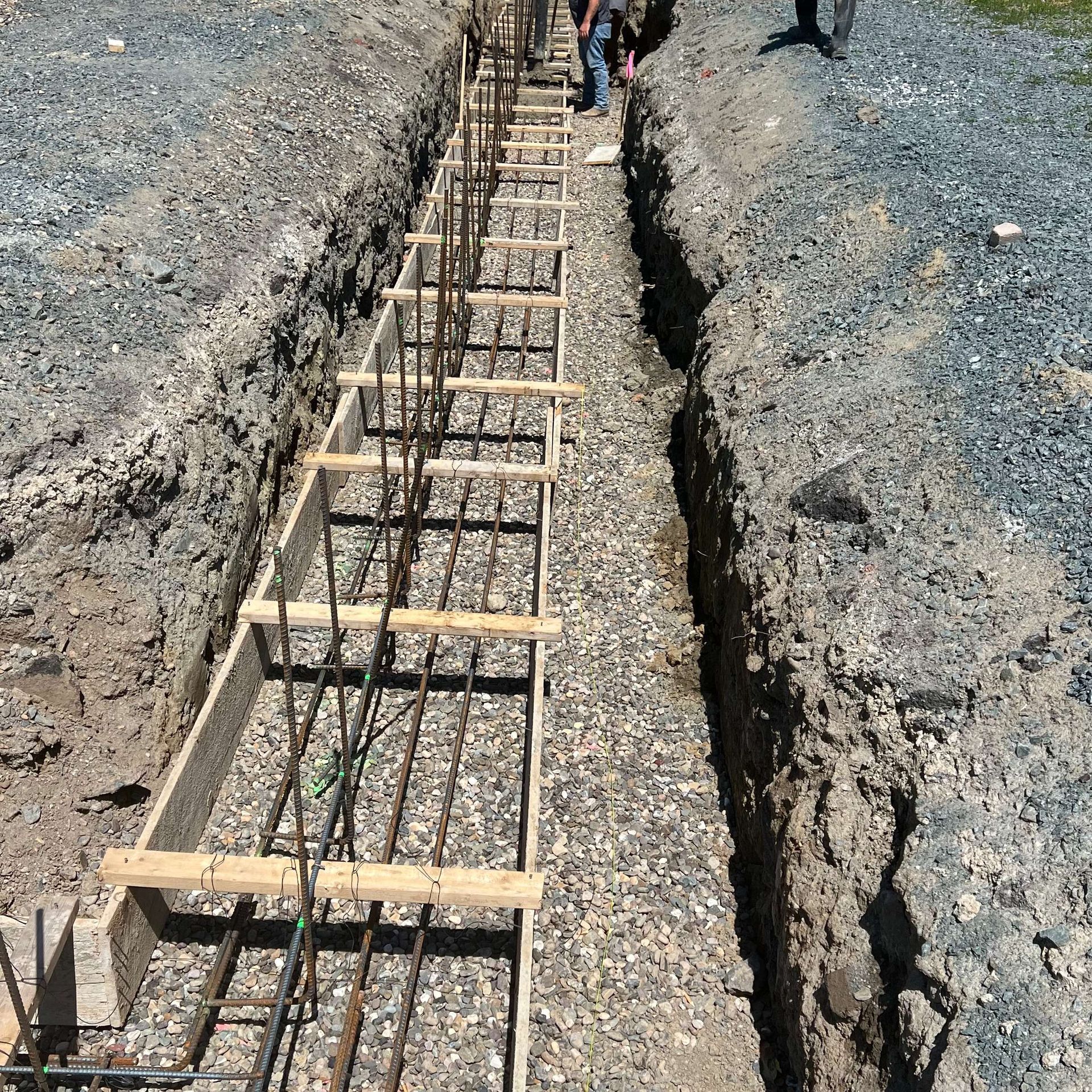 Construction site: Formwork and rebar in a trench, prepared for concrete foundation.