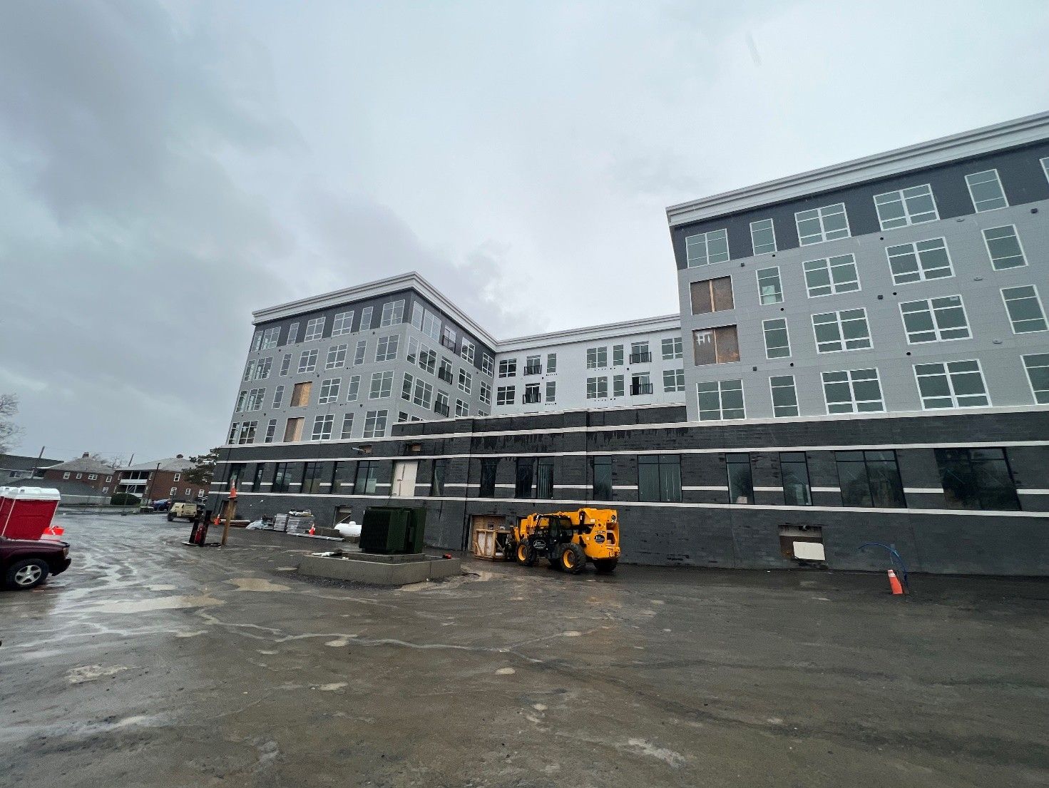 Multi-story building under construction with gray and black exterior panels under a cloudy sky.