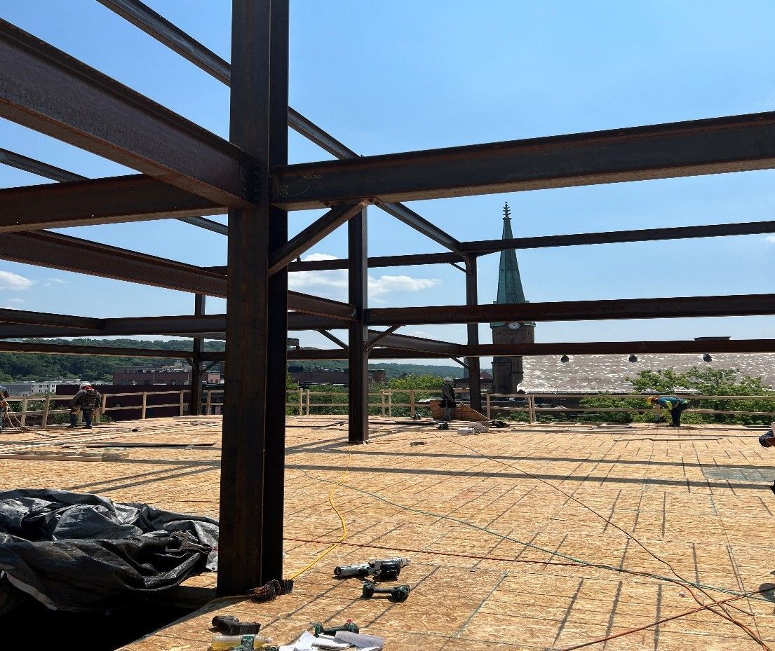 Steel frame construction with workers; cityscape in background.