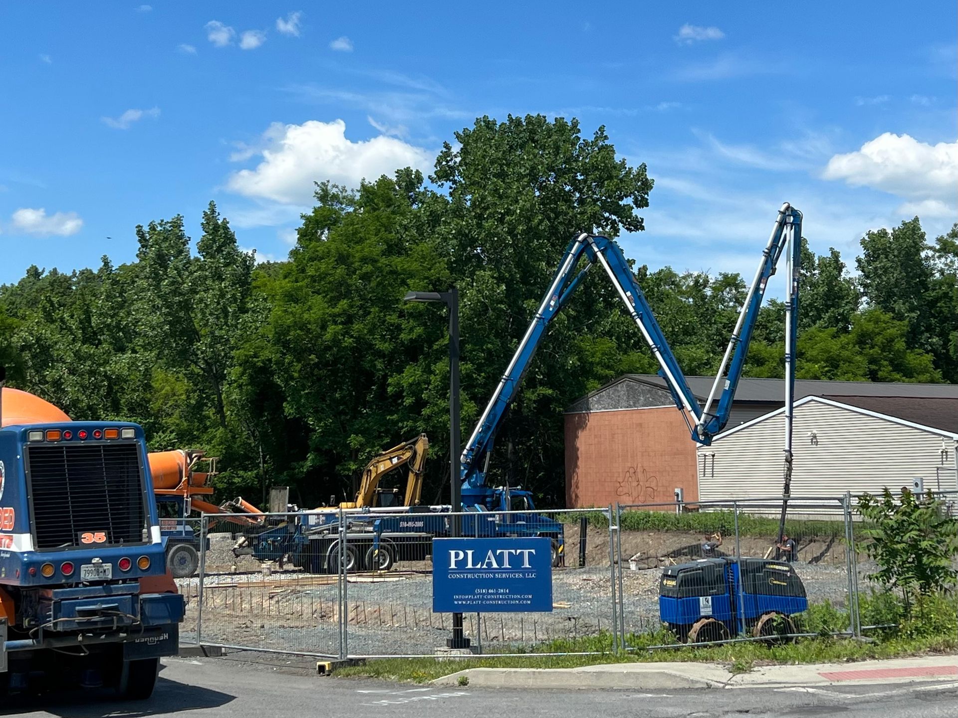 Construction site with a concrete pump truck extending over a building, blue sky.