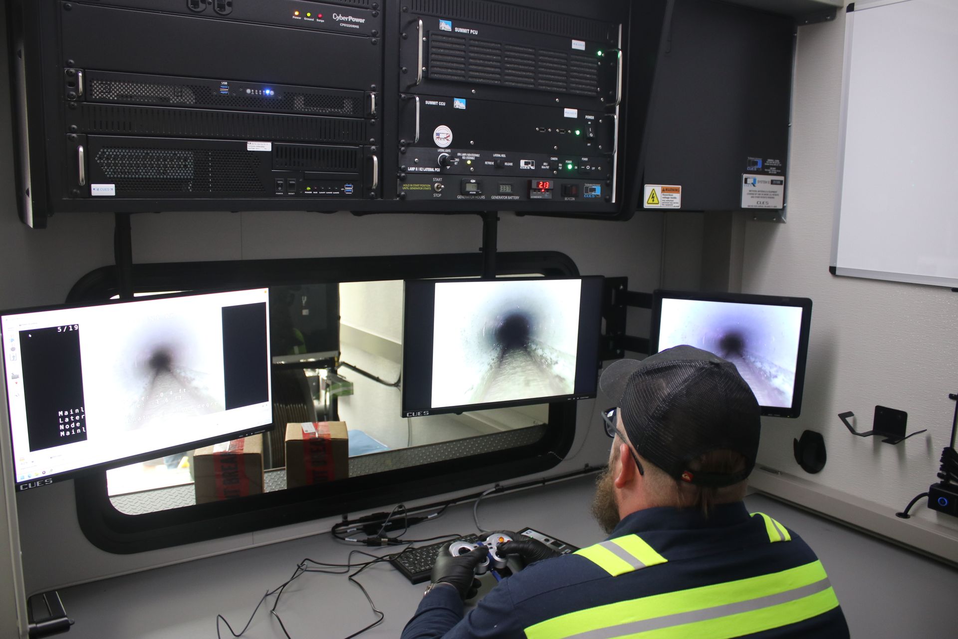 Technician at a workstation viewing bright monitor screens with dark, cloud-like images in a control room CCTV