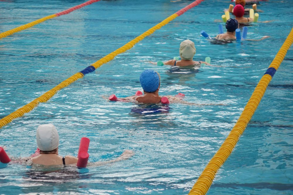 People Swimming in a Pool Using Flotation Devices — PhysioCare Townsville in Hyde Park, QLD