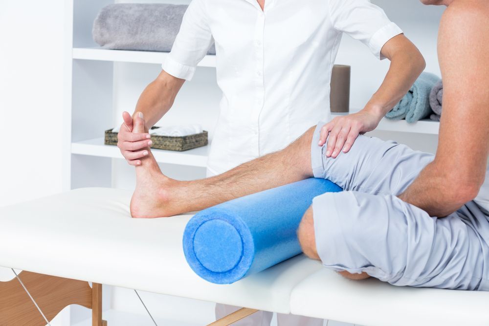 Physiotherapist Assisting a Person With a Leg Injury — PhysioCare Townsville in Deeragun, QLD