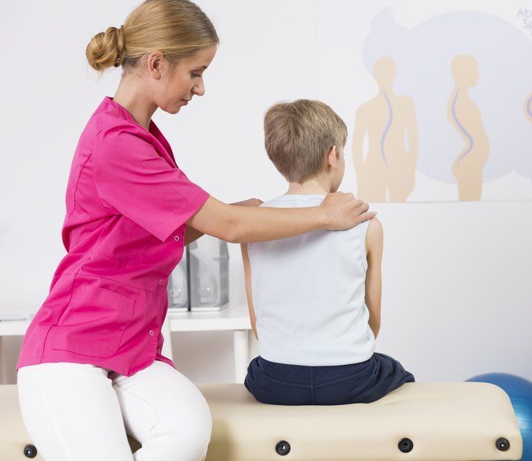 Therapist in Pink Scrubs Assesses a Child Posture — PhysioCare Townsville in Thuringowa Central, QLD