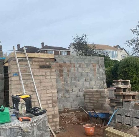 Block Work job completed with load bearing wall and a ladder stood up with tools and wheel barrow on the floor