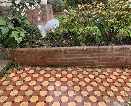 Brick retaining wall with flower bed and patterned tile flooring.