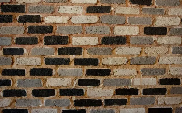 A close up of a brick wall with black , white and gray bricks.