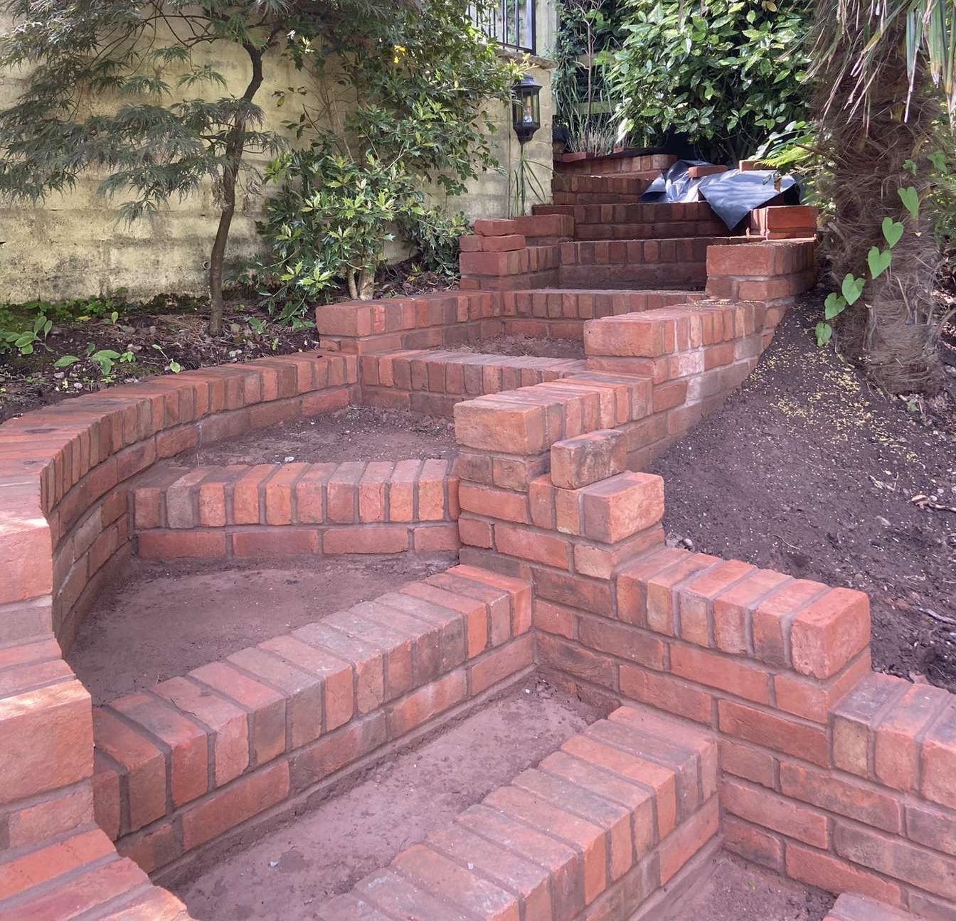 Patio steps Build patio steps built from bricks in a garden in the shade with flower beds next to it