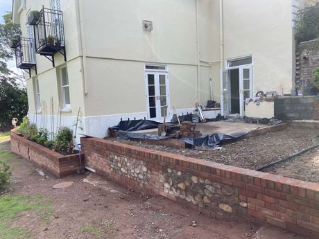 A picture of a retaining brick wall out the back of a house in the shade