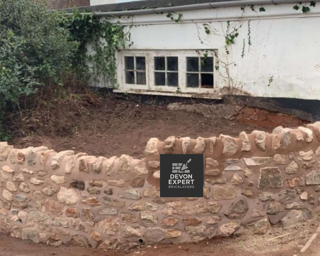 Brads Stunning retaining Wall retaining wall with brick pond in garden with mud on floor and bushes in background
