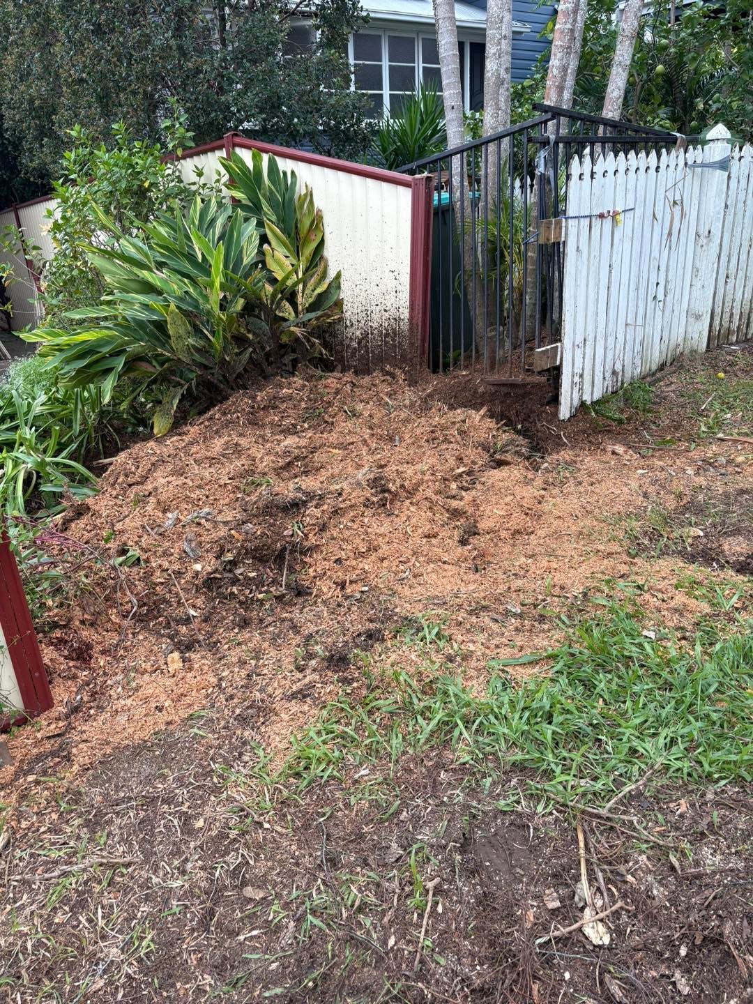 A Pile of Dirt is Sitting in Front of a White Picket Fence — All One Arb Tree Service In Bonny Hills, NSW