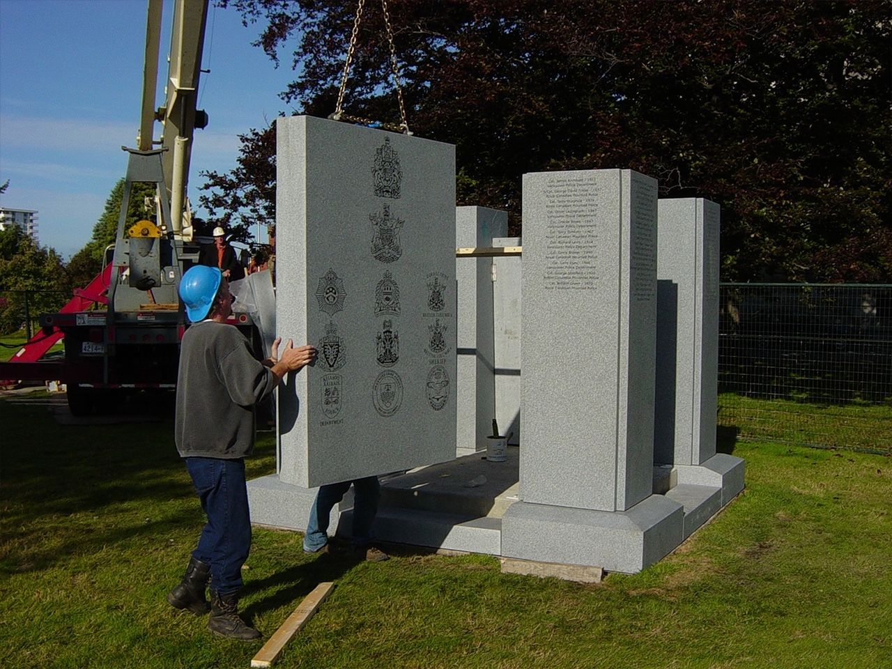 A man wearing a blue hard hat is carrying a large piece of granite