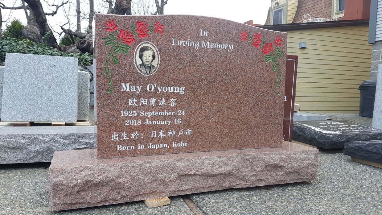 a gravestone with a picture of a woman on it is sitting on the ground .