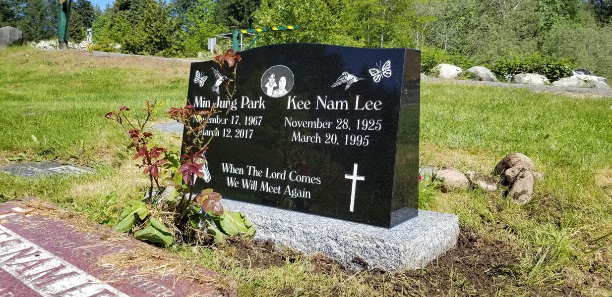 a black gravestone with a cross on it is in a cemetery .