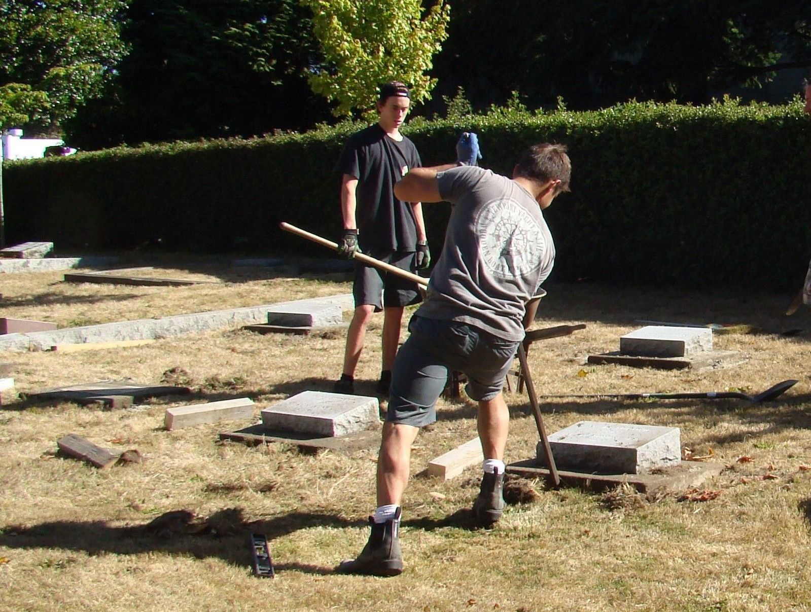 A man is digging in the grass with a shovel