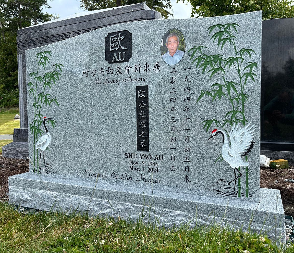 large grey granite headstone with Chinese characters, cranes and bamboo