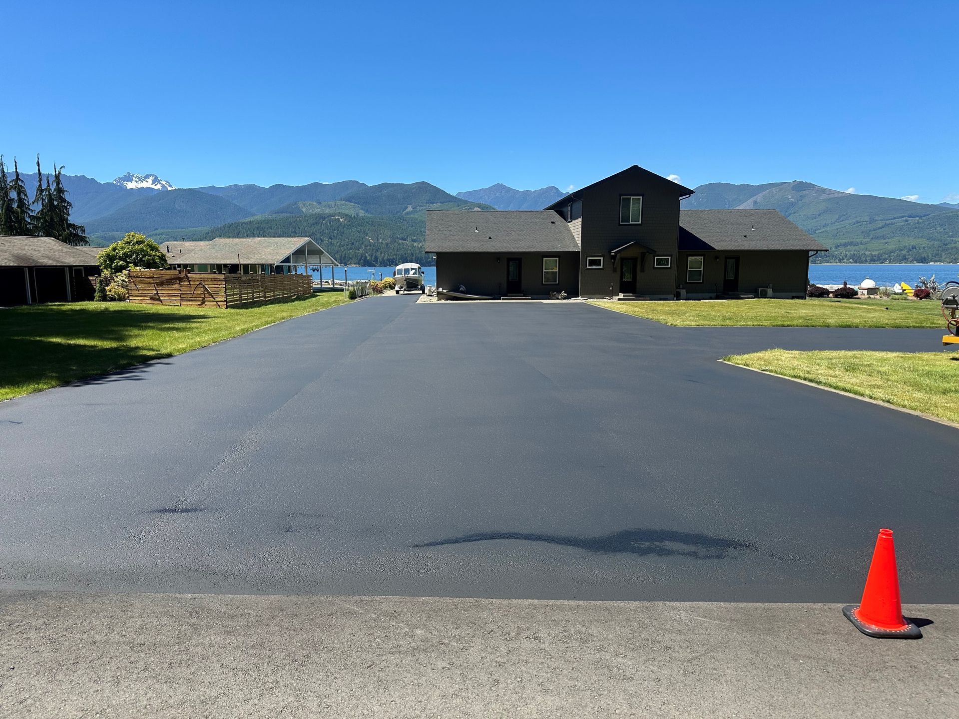 An orange roller is rolling asphalt on a road.