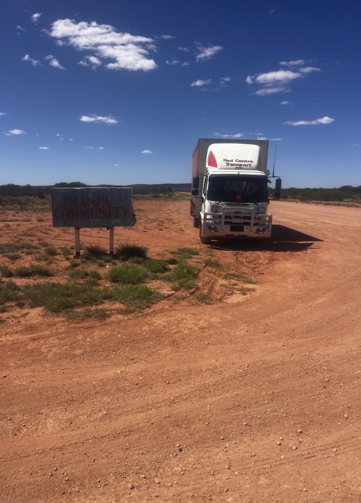 White van driving on a highway at sunset, fields on either side. — Red Centre Transport in Braitling, NT