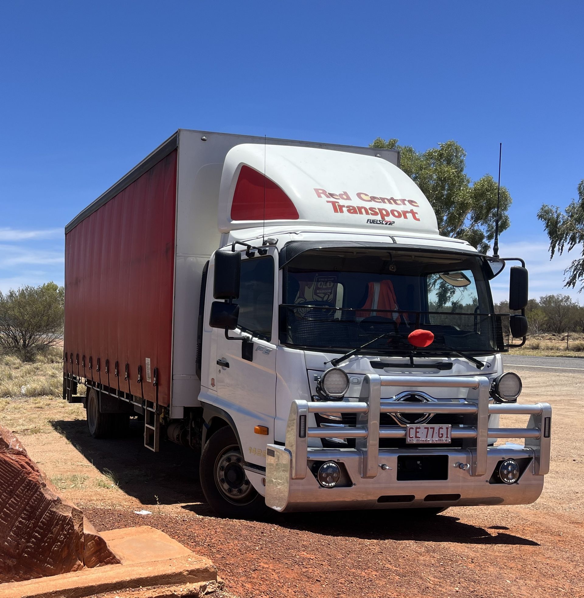 White-sided semi-truck driving on a road toward a blurred cityscape. — Red Centre Transport in Braitling, NT