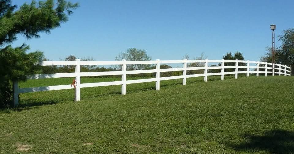 White fence along a grassy hill under a clear blue sky