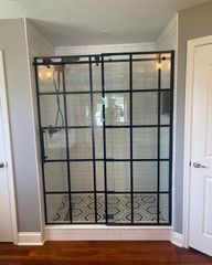 Black grid shower enclosure with patterned tile floor in a bathroom alcove