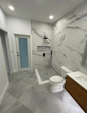 Modern bathroom with marble-tile shower, toilet, vanity, and gray floor tiles