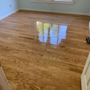 Shiny hardwood floor in an empty room with light blue walls and a window reflection.