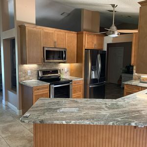 Modern kitchen with wooden cabinets, stainless steel appliances, granite counters, and a ceiling fan