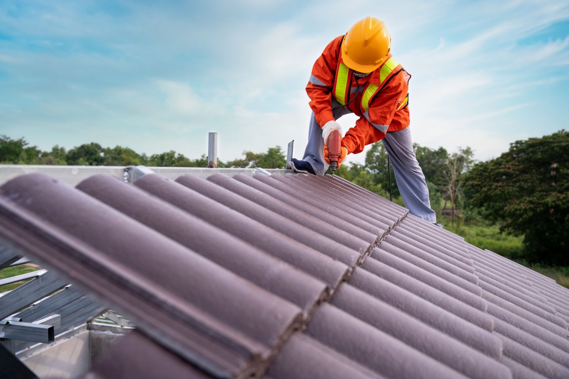 A worker using a drill to install a roof, showcasing commercial roofing installation process.