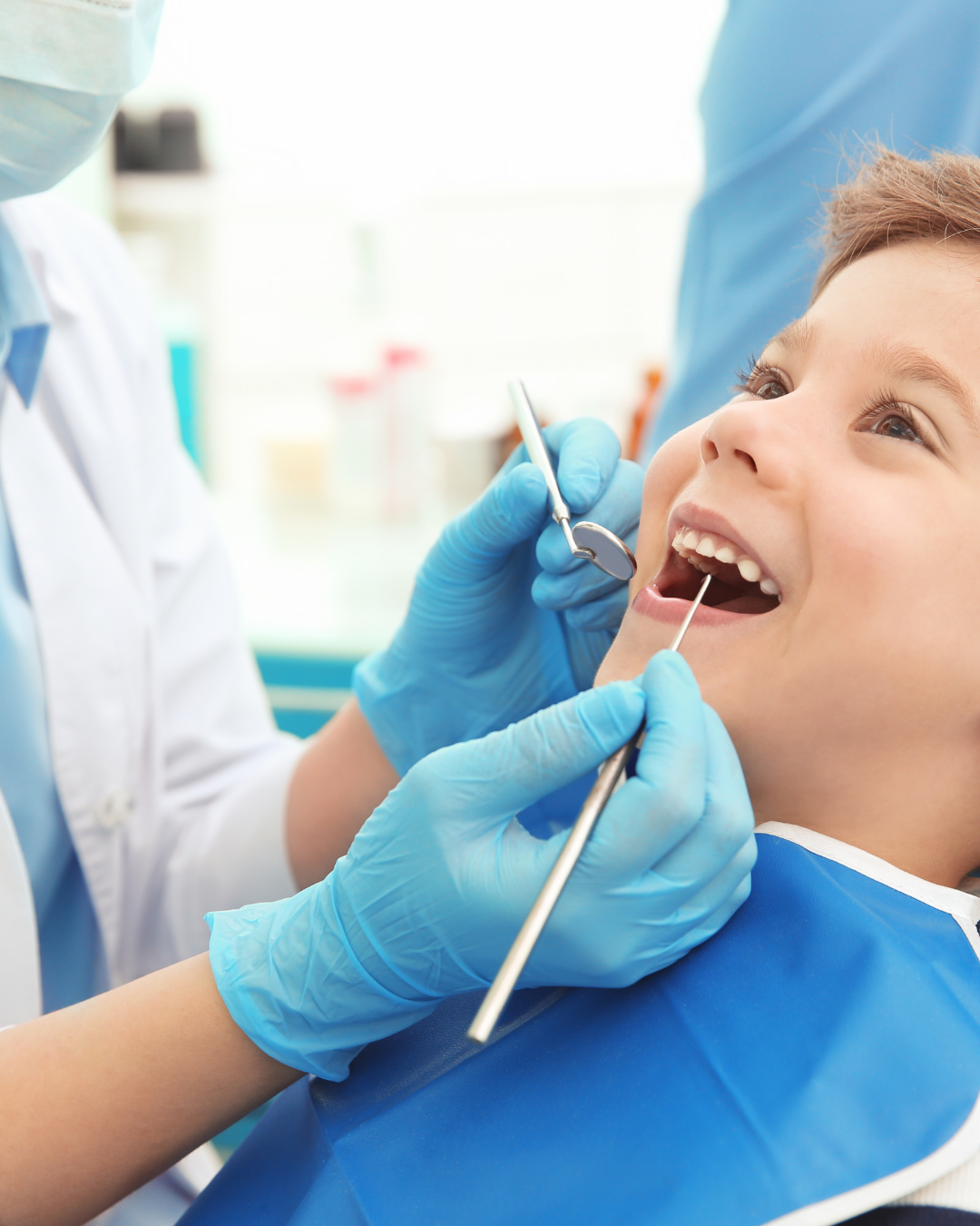Enfant chez le dentiste, bouche ouverte, examiné avec des instruments par des mains gantées.