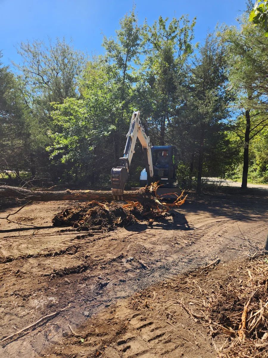 A large excavator is sitting in the middle of a dirt field.