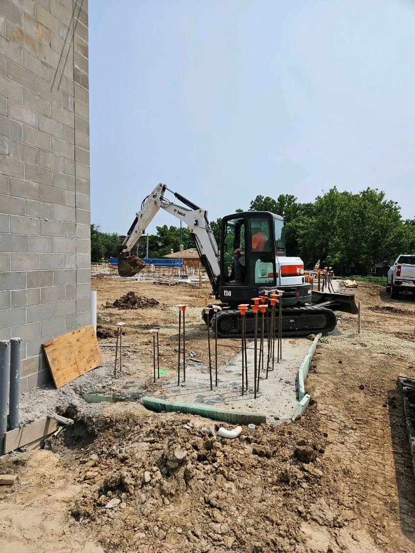 A small excavator is digging a hole in the dirt at a construction site.