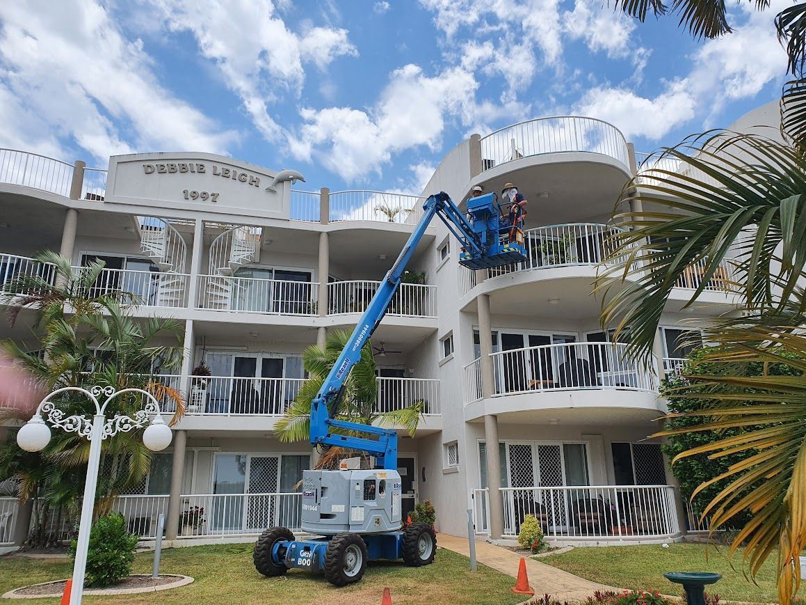 A man is using a crane to paint a building — Painter In Sunshine Coast, QLD